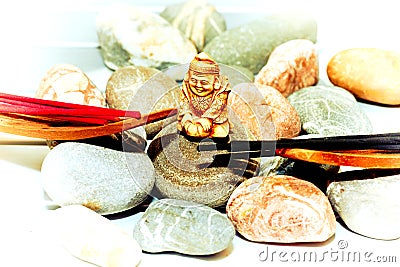 Statuette of a Buddhist monk among incense and various stones Stock Photo
