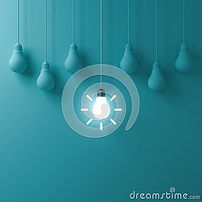 One hanging glowing idea light bulb standing out from dim unlit bulbs on green pastel color wall background Stock Photo