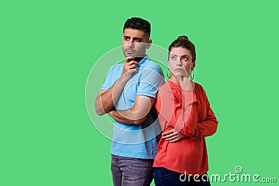 Think up plan! Portrait of smart attractive young couple in casual wear thinking together. isolated on green background Stock Photo