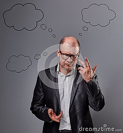 Thinking bald business man in eyeglasses discussing and have an idea on grey background. with empty clouds above the head. Closeup Stock Photo