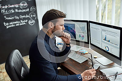 Thinking about business. Focused businessman, financial analyst holding eyeglasses and looking at graphs and charts on Stock Photo