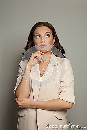 Thinking businesswoman on gray background portrait Stock Photo