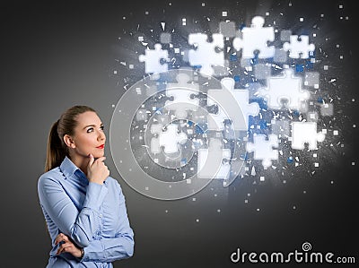 Thinking businesswoman looking at shining puzzle pieces Stock Photo