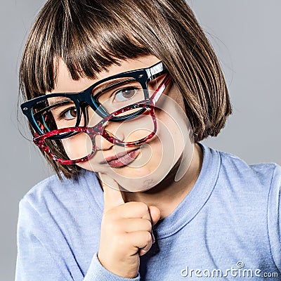 Thinking cheeky little kid trying many eyeglasses hesitating for choice Stock Photo