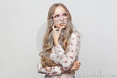 Thinking concept. Puzzlement long haired blonde woman in pink eyeglasses, touching her chin and looking up. Stock Photo