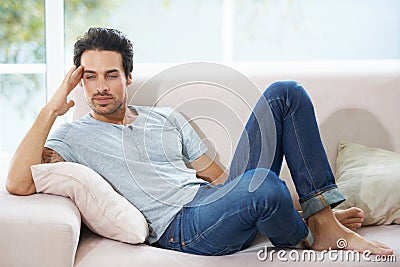 Thinking, depression and man on a sofa with stress, anxiety or broken heart in his home. Sad, crisis or male person in Stock Photo