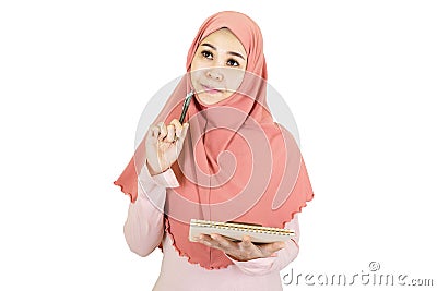 Thinking female - beautiful young muslim asian woman with traditional dress holding a pen and book look up and think isolated on Stock Photo