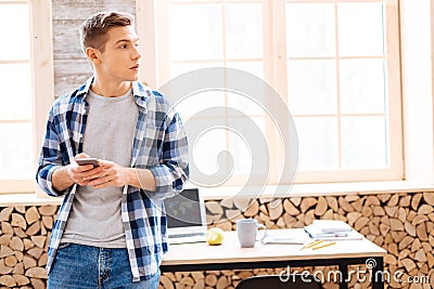 Thoughtful teenager holding his phone and thinking Stock Photo