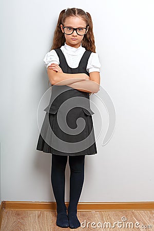 Thinking happy smiling pupil girl in fashion eyeglasses with folded arms in school uniform Stock Photo