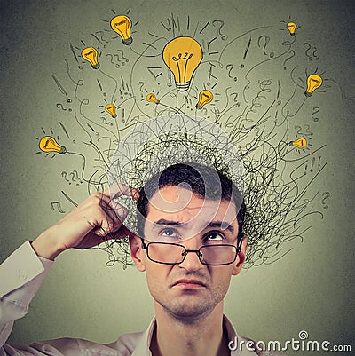 Thinking man with question signs and light idea bulbs above head looking up Stock Photo