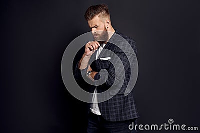 Thinking about something. Upset man with long hair and beard standing against grey background Stock Photo