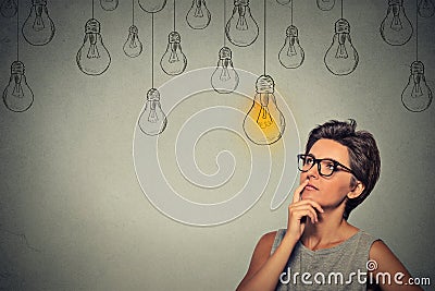 Thinking woman in glasses looking up with light idea bulb above head Stock Photo