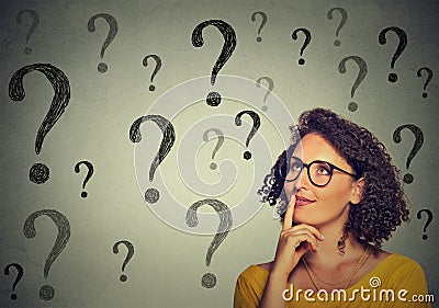 Thinking young business woman in glasses looking up at many question marks Stock Photo