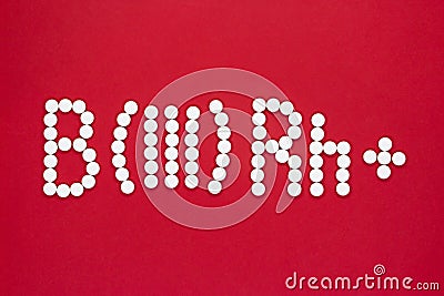 Third blood type. Blood type symbol from white pills on a red background. Blood type treatment Stock Photo