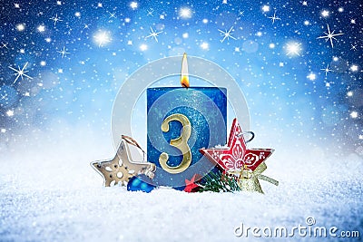 Third sunday of advent blue candle with golden metal number red decoration one on wooden planks in snow front of silver panorama Stock Photo