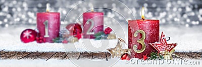 third sunday of advent red candle with golden metal number one on wooden planks in snow front of silver bokeh background Stock Photo