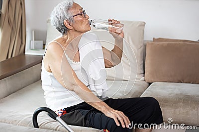 Thirsty senior woman suffering from heat,drinking fresh water from a bottle to quench their thirst in hot summer weather,high Stock Photo