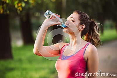 Thirsty woman drinking water to recuperate after jogging Stock Photo