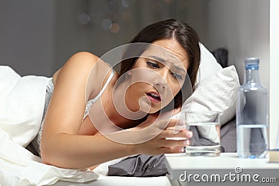 Thirsty woman reaching a glass of water in the night Stock Photo