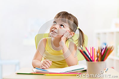 Thoughful child girl drawing with colorful pencils Stock Photo