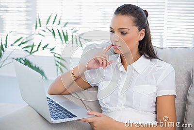 Thoughful woman looking at laptop Stock Photo