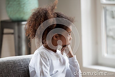 Thoughtful African American preschooler girl looking in window Stock Photo