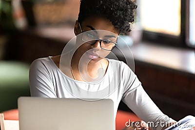 Thoughtful biracial girl in glasses focused studying on laptop Stock Photo