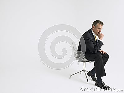 Thoughtful Businessman Sitting Against Gray Background Stock Photo