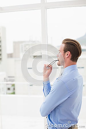 Thoughtful businessman standing and holding his glasses Stock Photo