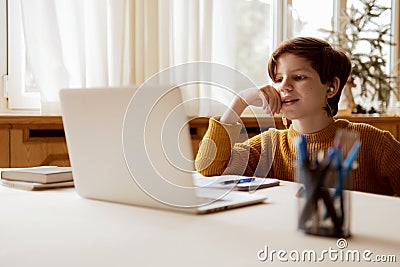 A thoughtful child listens to a teacher in an online class Stock Photo