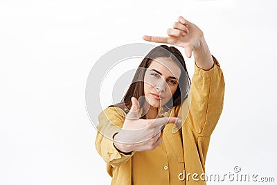 Thoughtful creative woman searching perfect shot, making hand frames camera gesture and looking through pensive Stock Photo