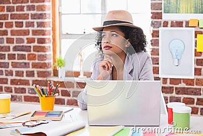 Thoughtful female interior designer at desk Stock Photo