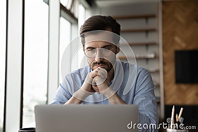 Thoughtful focused business man in glasses working at laptop computer Stock Photo