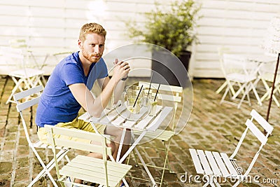 Thoughtful ginger male waiting at a table outdoors Stock Photo
