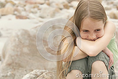 Thoughtful Girl Sitting On Rock Stock Photo