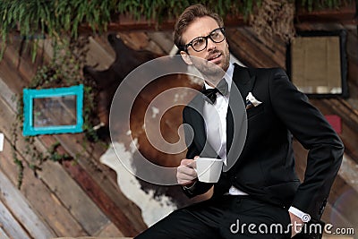 Thoughtful groom holding a coffee cup and looking away Stock Photo