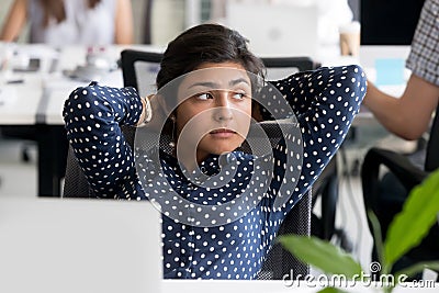 Thoughtful Indian female employee leaning back in chair at workp Stock Photo