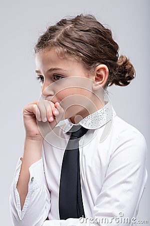 Thoughtful little schoolgirl with hand to mouth Stock Photo