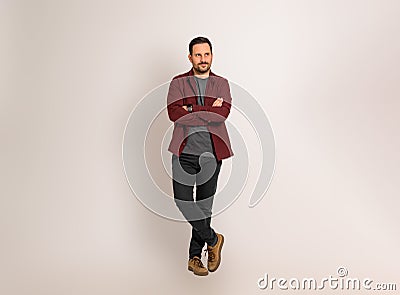 Thoughtful man with arms crossed looking away while standing isolated against background. Handsome young man dressed in maroon Stock Photo