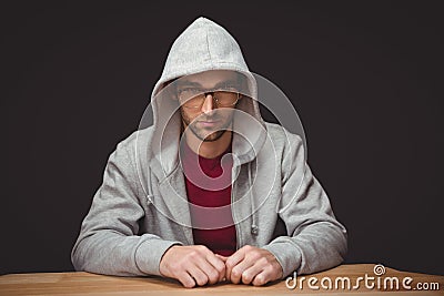 Thoughtful man with hooded shirt sitting at desk Stock Photo