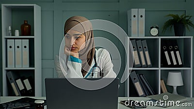 Thoughtful sad bored young therapist doctor woman sitting at clinic alone worried unmotivated lazy female physician Stock Photo