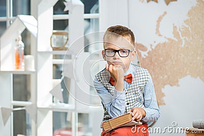 A thoughtful schoolboy sits at a desk with books Stock Photo