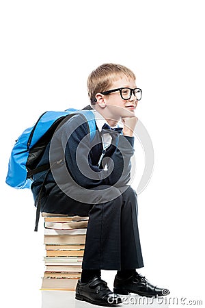 thoughtful schoolboy sitting on a pile of books on a white background Stock Photo