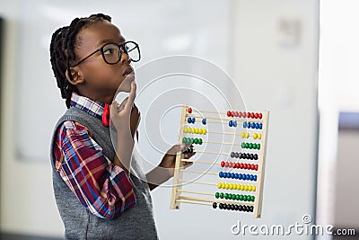 Thoughtful schoolboy using a maths abacus in classroom Stock Photo