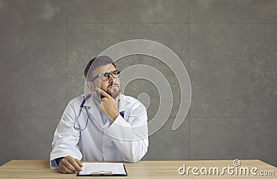 Thoughtful serious millennial doctor rubbing chin while thinking of diagnosis Stock Photo