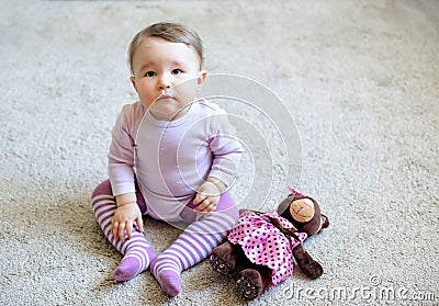 Thoughtful and serious nice baby girl sitting on the floor Stock Photo