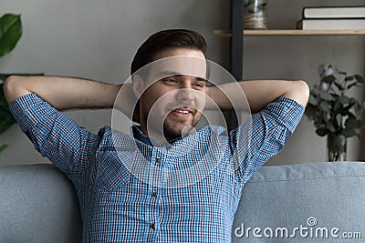 Thoughtful smiling guy relaxing on couch, looking away and smiling Stock Photo