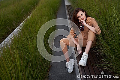 Thoughtful smiling young beautiful red haired gen z girl wearing slim fitted women beige khaki coverall overall denim Stock Photo