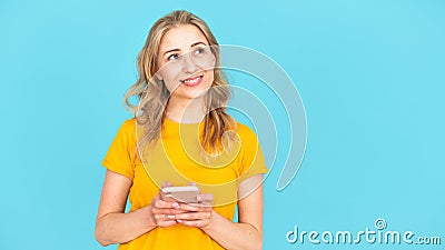 Thoughtful and smiling young woman looking aside, holding modern cellphone Stock Photo
