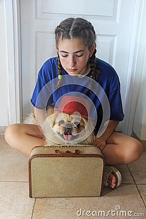 A thoughtful teenage girl with pekingese dog and a suitcase Stock Photo